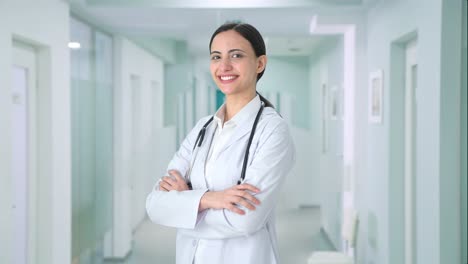 retrato de una feliz doctora india de pie con las manos cruzadas