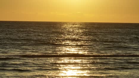 pequeñas olas en un mar tranquilo durante la puesta de sol