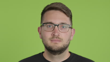 Mann-Mit-Brille-Entfernt-Schützende-Kn95-Gesichtsmaske,-Während-Er-Auf-Greenscreen-Chroma-Key-Aus-Nächster-Nähe-In-Die-Kamera-Blickt