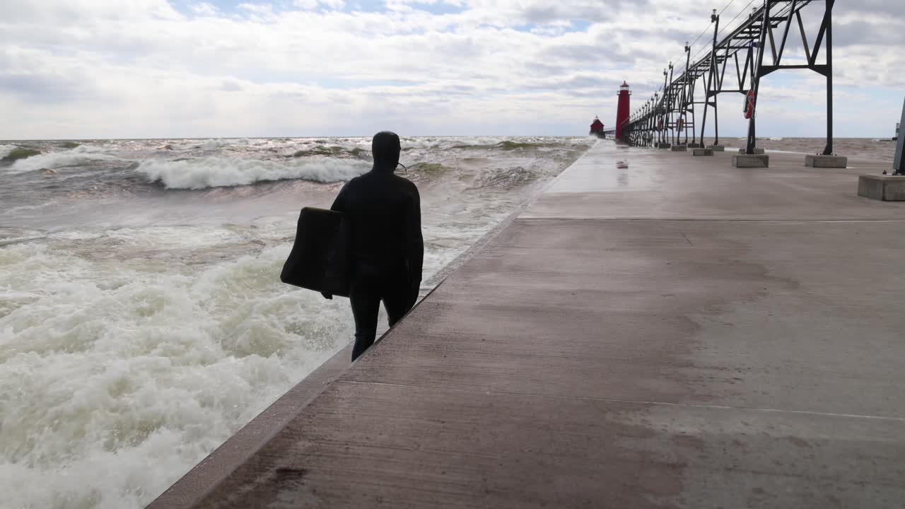 그랜드 헤이븐에서 서퍼 뒤를 걷고, 미시간 호수의 미시간 부두에서 느린 동작으로