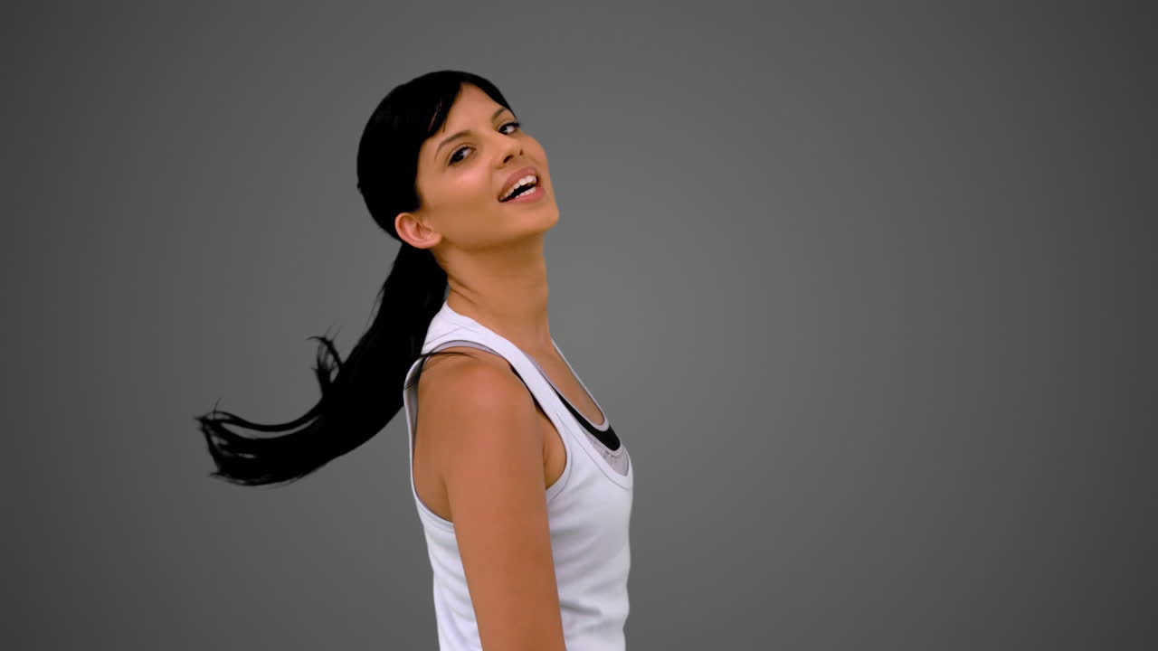 카메라를 향해 미소 짓고 머리를 흔들고 있는 잘생긴 갈색 여자