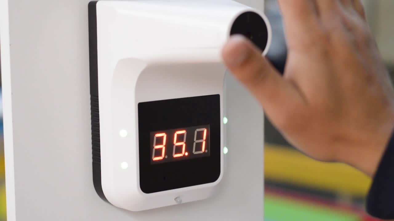 мужчина измеряет температуру инфракрасным термометром в рамках плановой проверки ковида-19