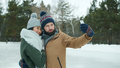 couple taking a selfie at a winter ice rink