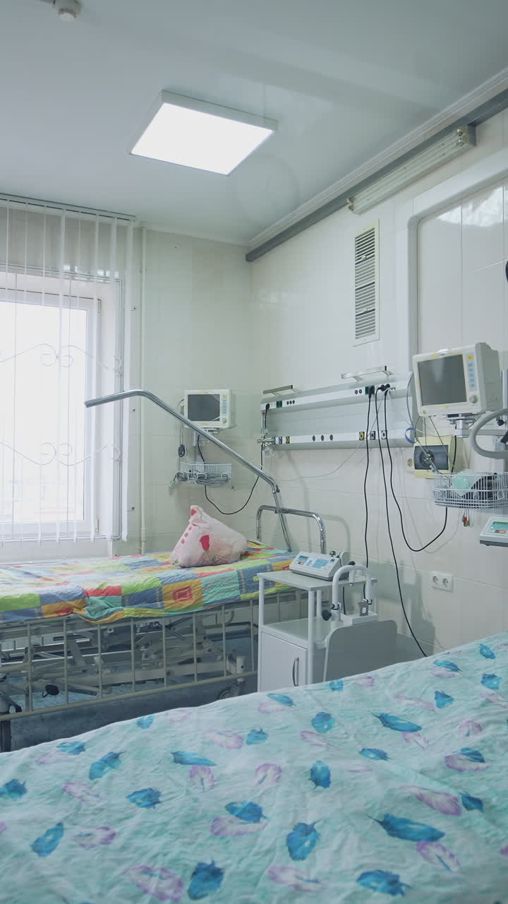 Modern resuscitation room with hospital beds. Medical ward with new equipment near beds. Hospital ward with empty beds. View into the ward through window. Vertical video