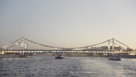 cable-stayed bridge over a river at dusk with boats