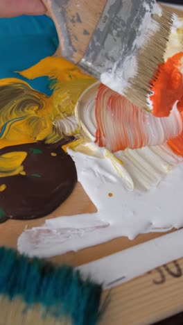 close-up of a paint palette with a brush mixing colors