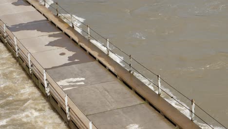 el agua fangosa de la inundación en la corriente del río rápido casi desborda el puente angosto