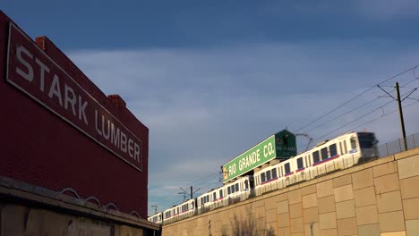 un tren de tránsito rápido se mueve a través de un área industrial en denver colorado