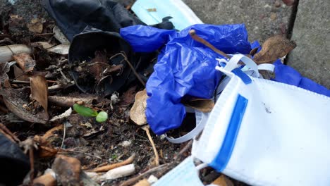 dirty infectious disposable corona virus face masks and latex gloves among cigarette rubbish on street curb dolly right