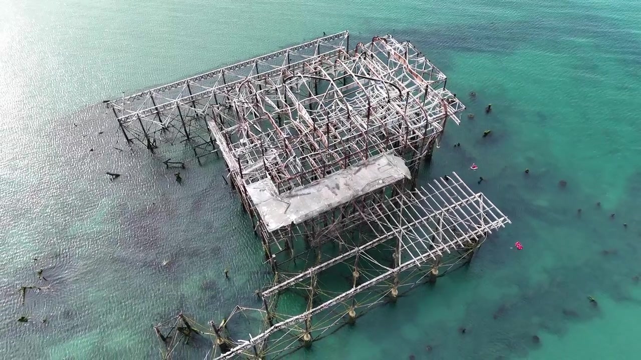 Luftaufnahmen mit Drohne von Brightons verfallener West Pier bei historischer Ebbe, die seltene viktorianische Fundamente und verborgene Eisenkonstruktionen unter der Küste von Sussex enthüllen