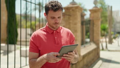 Young hispanic man watching video on touchpad at street