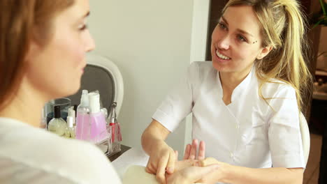 smiling beauty therapist massaging customers hands