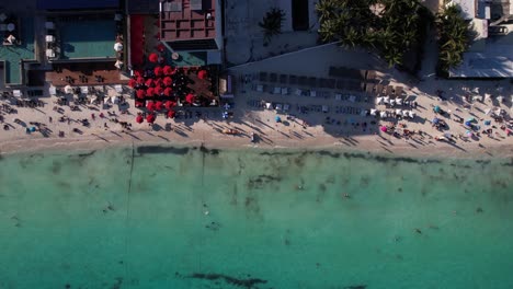 Birdseye-Aerial-View-of-Tropical-Beachfront-Resort,-People,-Swimming-Pools-and-Turquoise-Sea-Water