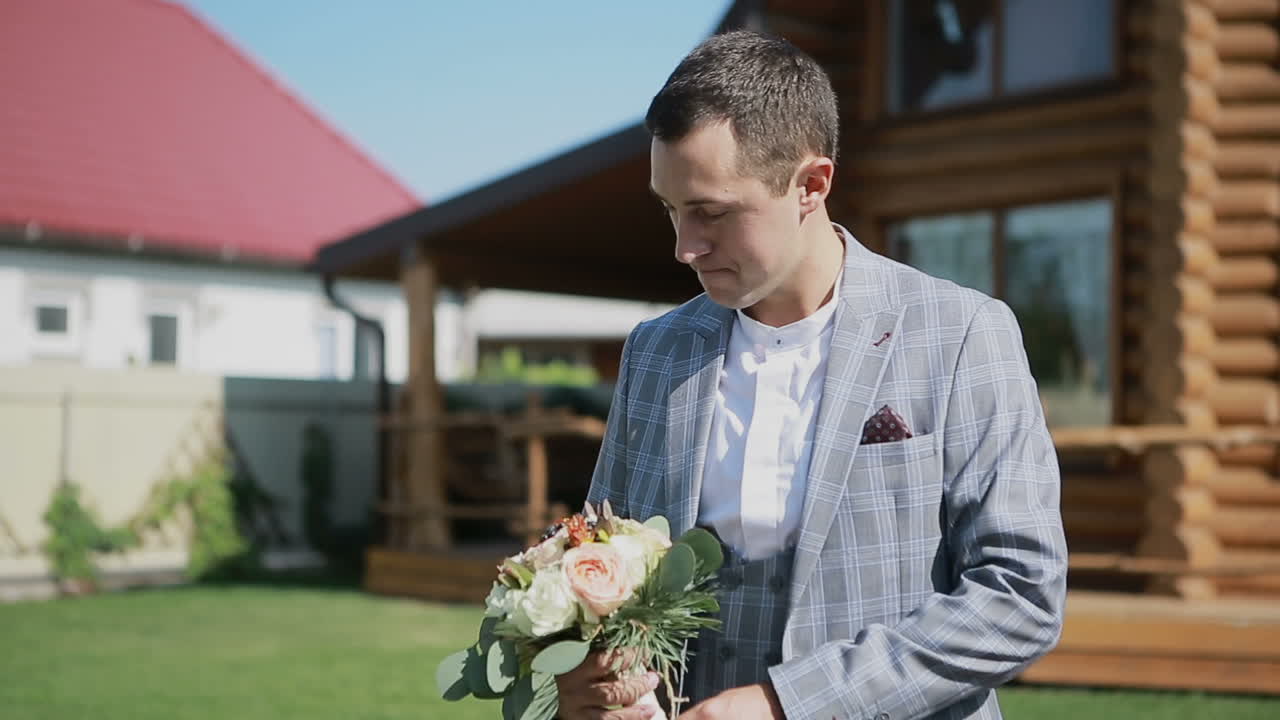 Handsome man holding a bouquet. Groom prepares for a wedding