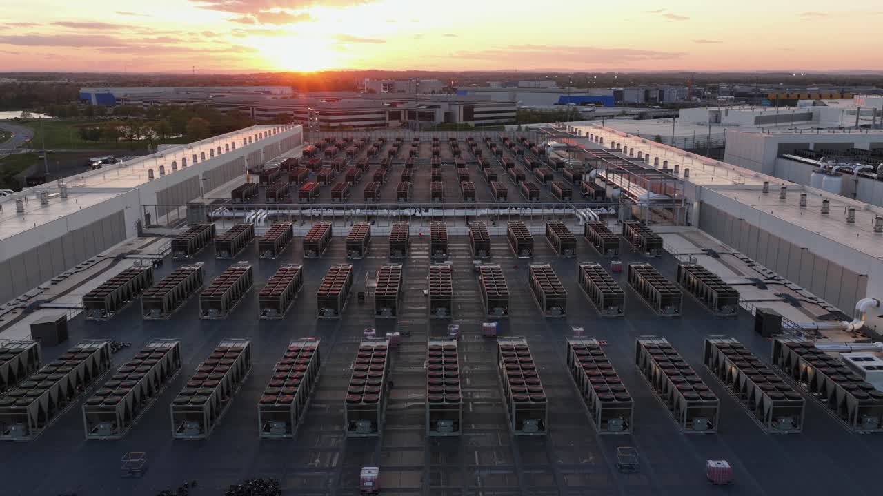 Luftfoto med drone af et moderne datacenterkompleks i Ashburn, Virginia, USA ved solnedgang, der viser kølesystemer på taget, teknologisk infrastruktur og et omfattende serverfacilitetskompleks.