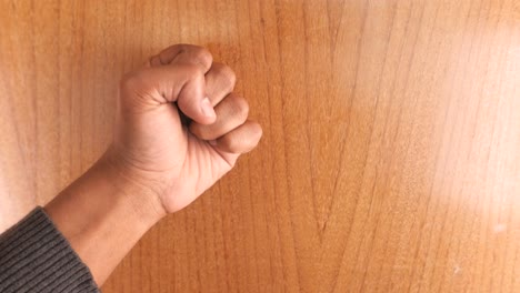 person's fist on a wooden surface