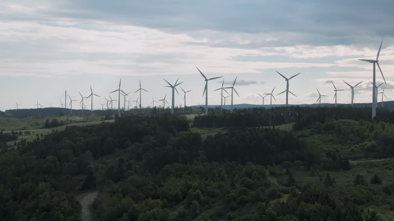 Panoramic View Of White Wind Turbines With Propelling Blades On Lush Green Field Near St. Lawrence River In Northern Quebec, Canada - Wide Shot