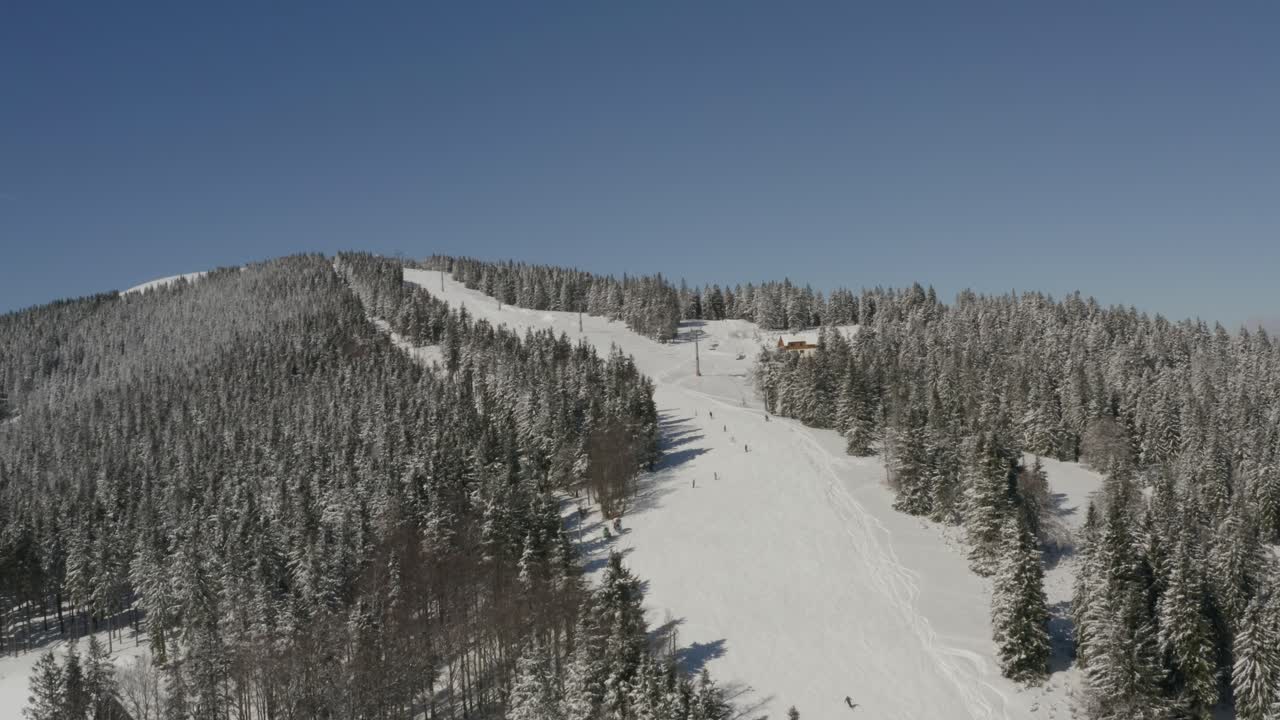 Centro sciistico Kope in Slovenia con la pista Ribnica One popolata da sciatori in discesa, ripresa aerea in avvicinamento