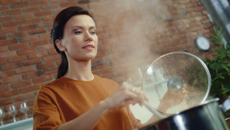 mujer elegante mezclando sopa con cuchara. niña joven oliendo comida de la olla hirviendo.