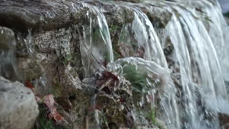 Panning-close-up-shot-of-small-waterfall,-slow-motion