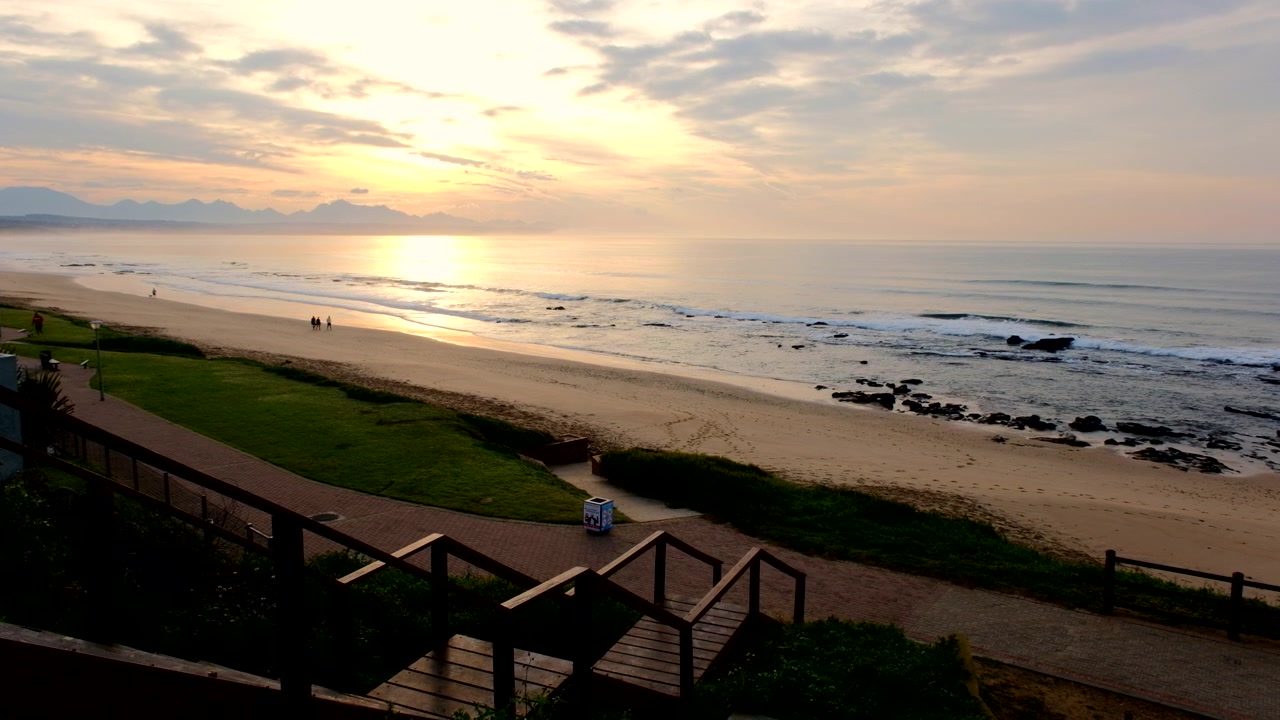 Vibrant coastal sunrise over ocean with view over Hartenbos beachfront walkway
