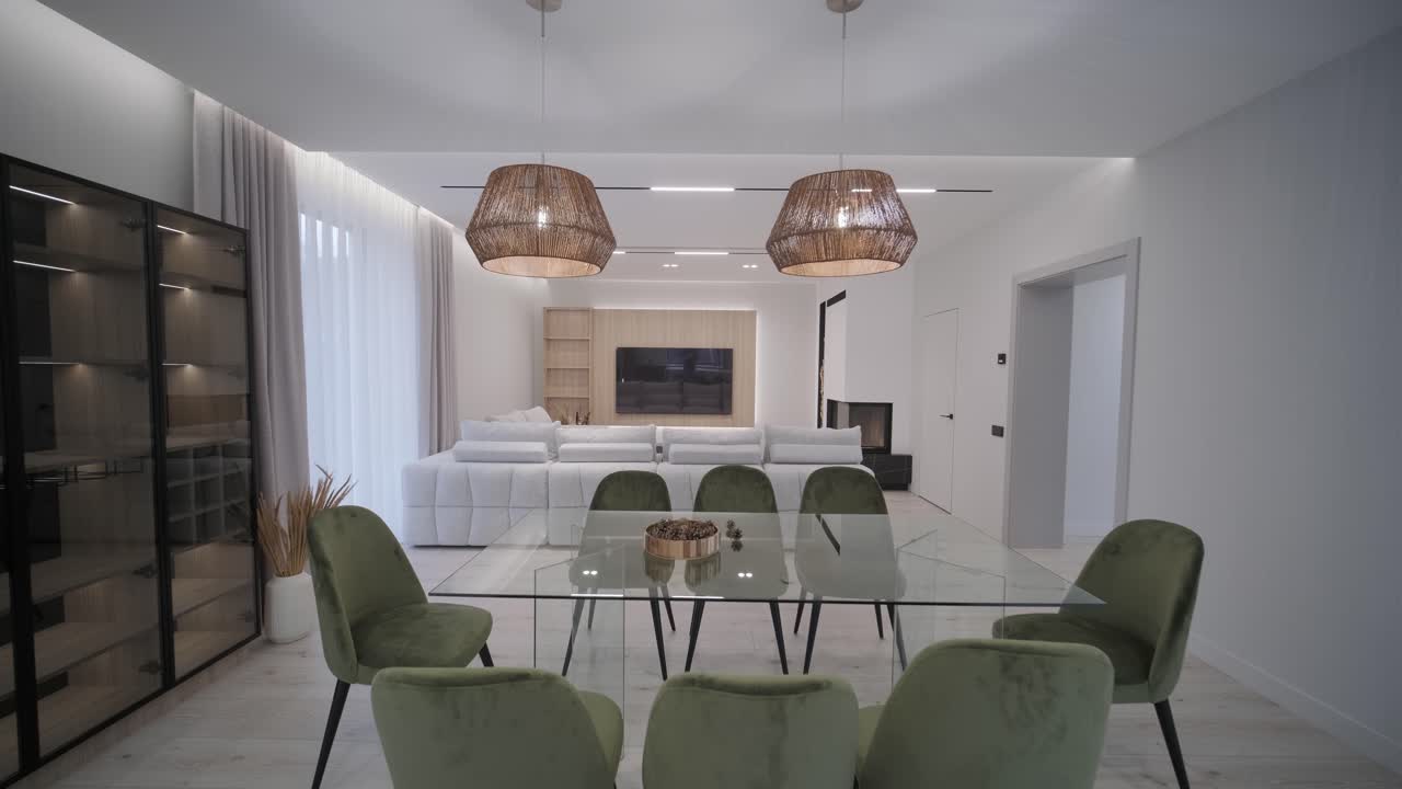 área de comedor moderna y elegante con elegantes sillas verdes, una mesa blanca, y luces colgantes de mimbre, acentuadas por tonos neutrales y luz natural