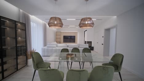 modern and stylish dining area with elegant green chairs, a white table, and wicker pendant lights, accented by neutral tones and natural light