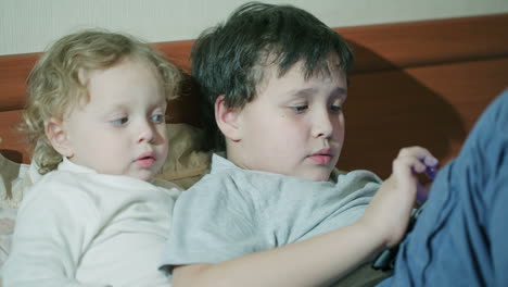 two young children playing with a tablet