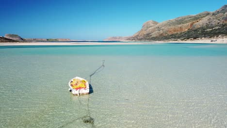 a boat on an empty white sand beach with turquoise water.  paradise. balos beach, crete, greece