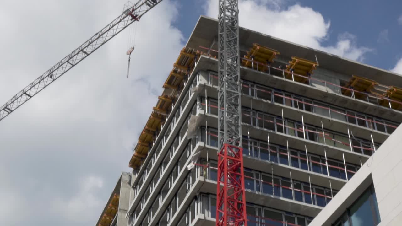 inclinar hacia abajo la toma de un edificio de apartamentos bajo obras con una grúa grande