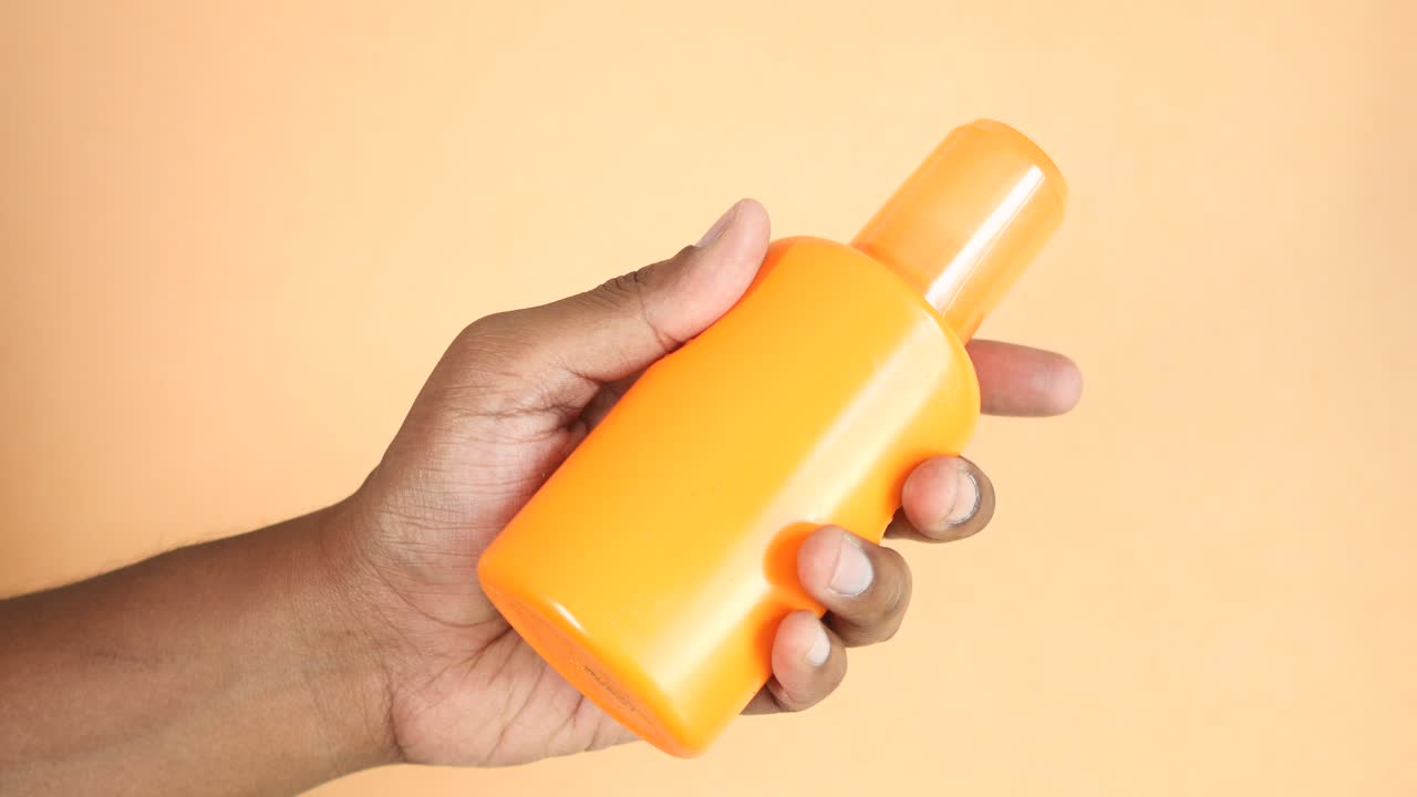 Hand holding a bottle of sunscreen
