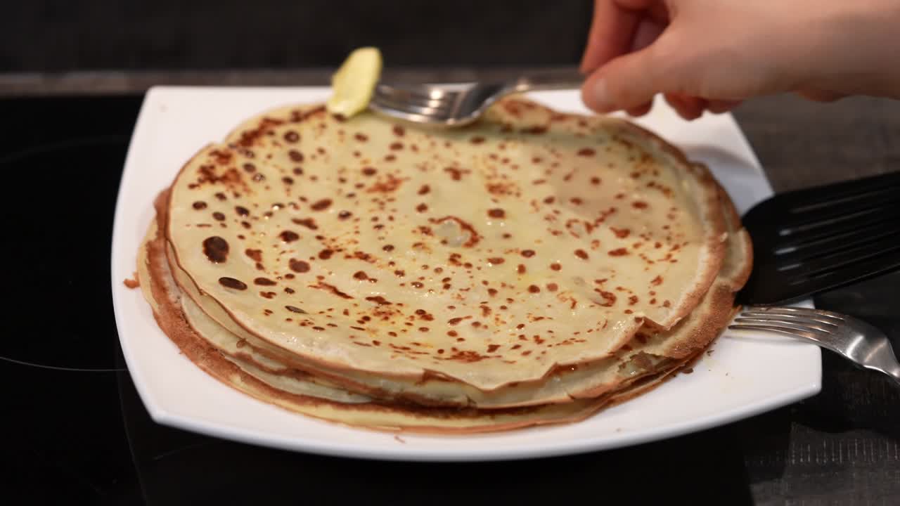 Pancakes on a plate and grease with butter. Big pancake. Cooking smoke goes up from pancake. Big pancakes with holes. Pancake weekend. Russian tradition