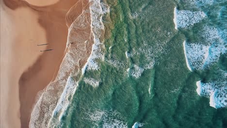 Toma-Aérea-De-Arriba-Hacia-Abajo-De-Olas-Del-Océano-Atlántico-Llegando-A-La-Playa-Dorada-Con-Gente-En-Verano