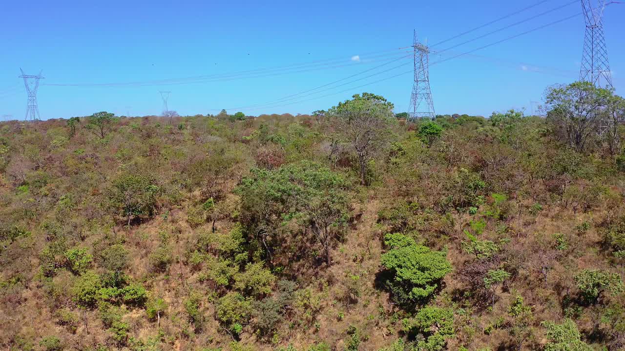 Power transmission lines traversing Brazilian Cerrado ecosystem, revealing native vegetation and water sources amid industrial infrastructure's environmental integration