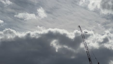 Airplane flying above clouds with a crane, daytime travel scene