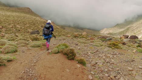 tired tourist walks to the tacheddirt pass in high atlas, morocco