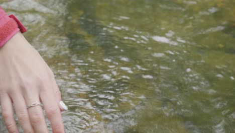 woman's hand touching a stream