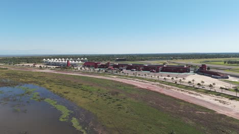 el dron avanza sobre el embalse río hondo, revelando el vasto circuito internacional de las termas de río hondo en un soleado día de verano.