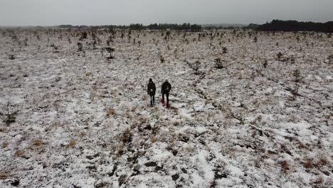 Luftdrohnenansicht-Eines-Paares,-Das-Mit-Schneeschuhen-In-Einer-Kargen-Moorlandschaft-Spazieren-Geht