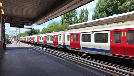 london underground train arriving at an outdoor station platform