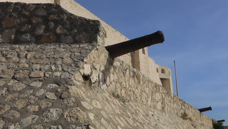 old stone walls of a tunisian castle with historic cannons against a clear blue sky