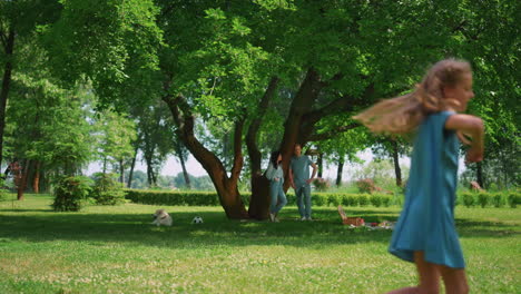 pretty girl escaping brother on green lawn. playful sister run in park outdoors.