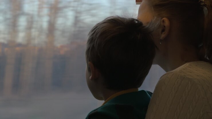 Mother and child looking out train window during the travel