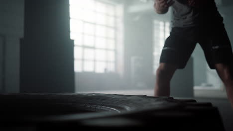 man hitting rubber tire with hammer. guy practicing exercise with sledgehammer