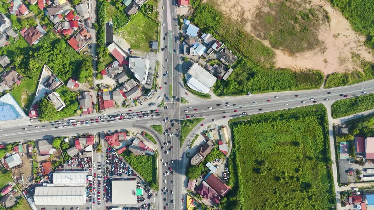 Aerial top-down view of Kota Bharu, Malaysia, capturing a busy traffic intersection surrounded by urban buildings, greenery, and mixed-use city areas in daylight