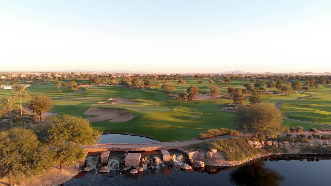 Drone footage from a golf course near a residential neighborhood in Arizona. High to low aerial shot from a shot of the greens to the water hazard