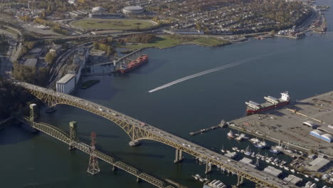 vehicles driving at iron workers memorial bridge next to second narrows rail bridge over burrard inlet in vancouver, british columbia, canada