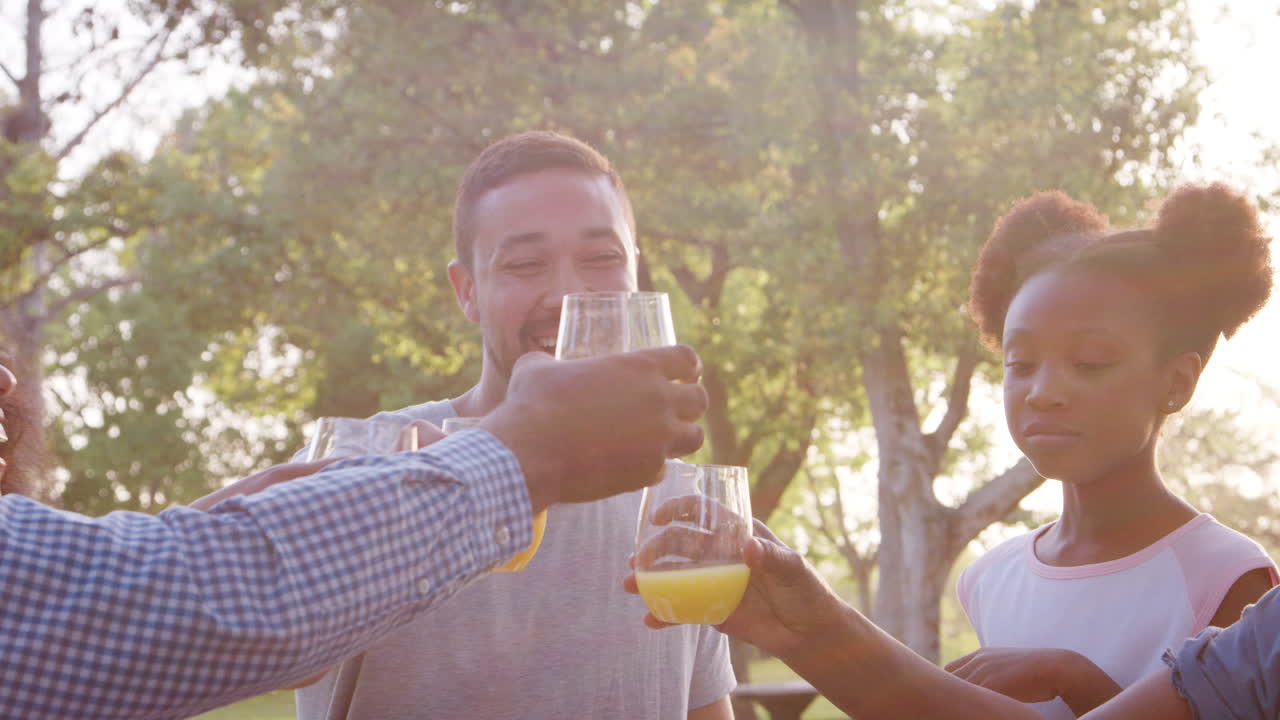 familia de varias generaciones haciendo tostadas con jugo en un picnic en el parque