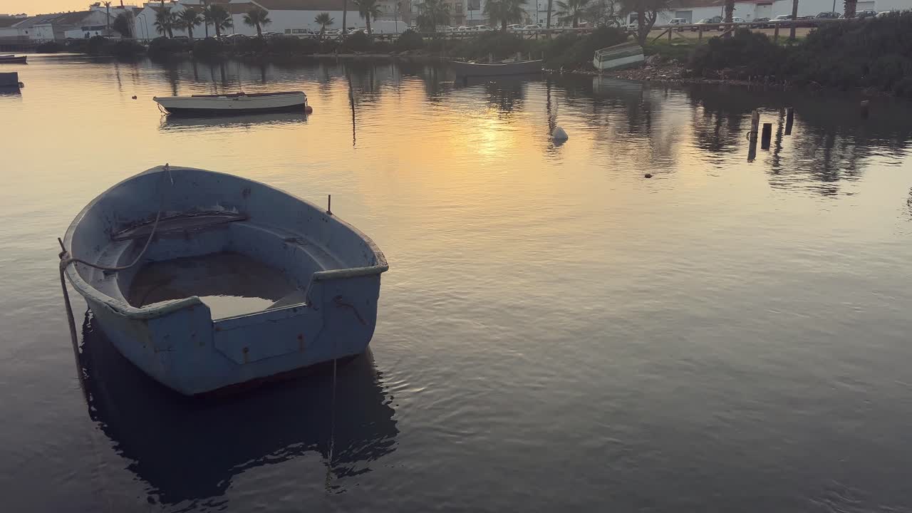 puesta de sol sobre un tranquilo canal con viejos barcos