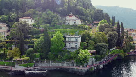 aerial view of buildings in the hills of lake como as groups of tourists walk along the coast